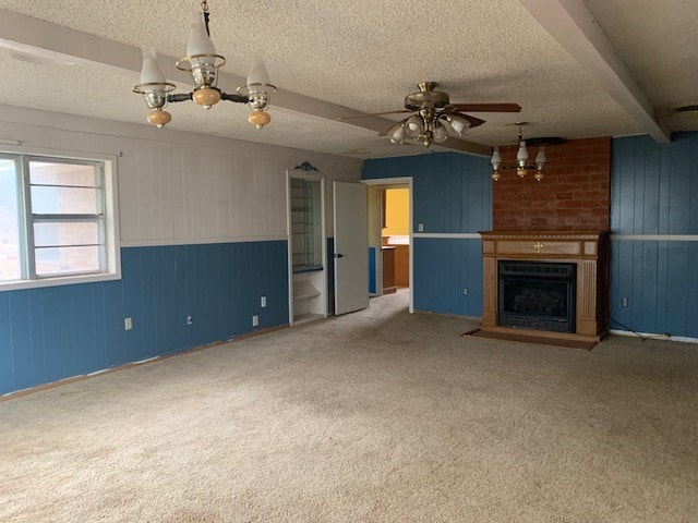 unfurnished living room with ceiling fan with notable chandelier, a large fireplace, a textured ceiling, carpet floors, and beam ceiling