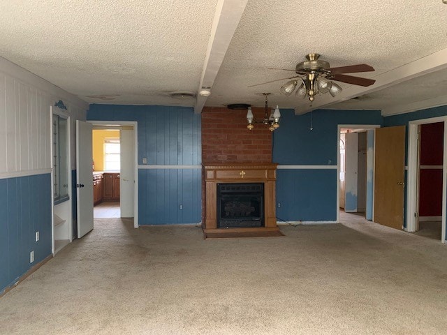 unfurnished living room with beamed ceiling, carpet, a textured ceiling, a fireplace, and ceiling fan