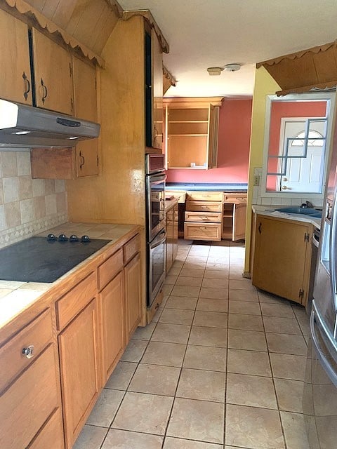 kitchen featuring tasteful backsplash, light tile patterned floors, black cooktop, tile counters, and stainless steel double oven