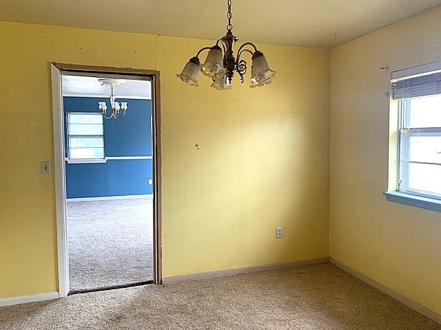 unfurnished dining area with a chandelier and carpet