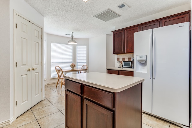 kitchen featuring white fridge with ice dispenser, decorative light fixtures, light tile patterned flooring, and a kitchen island