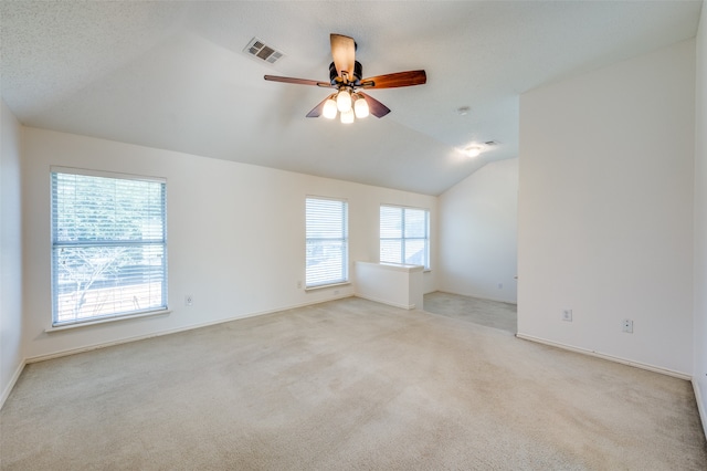 unfurnished room featuring a textured ceiling, vaulted ceiling, light colored carpet, and ceiling fan