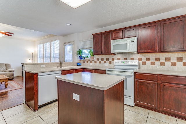 kitchen featuring white appliances, light hardwood / wood-style floors, a center island, and ceiling fan