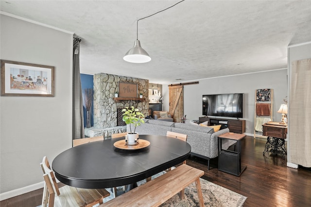 dining space with built in shelves, a barn door, dark hardwood / wood-style floors, a textured ceiling, and a fireplace