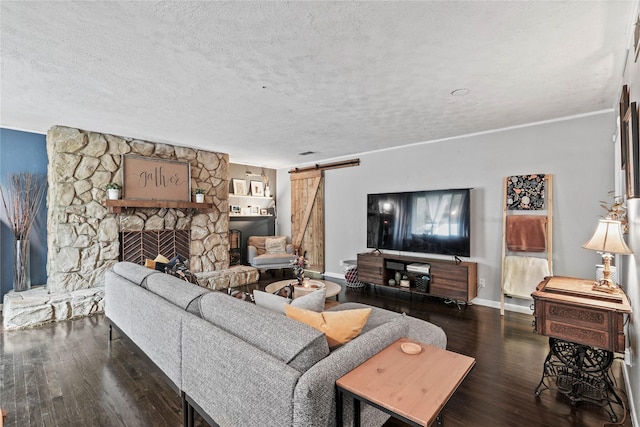 living room with dark hardwood / wood-style floors, a fireplace, a barn door, and a textured ceiling