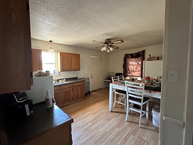 kitchen with light wood-type flooring, a textured ceiling, ceiling fan, pendant lighting, and white fridge