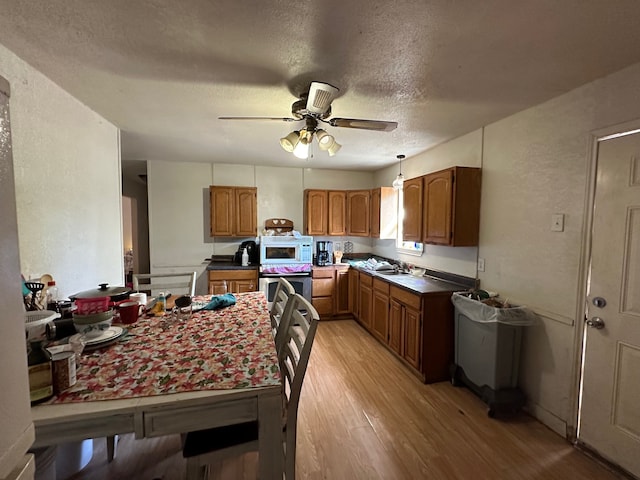 kitchen featuring stainless steel oven, light hardwood / wood-style flooring, sink, a textured ceiling, and ceiling fan