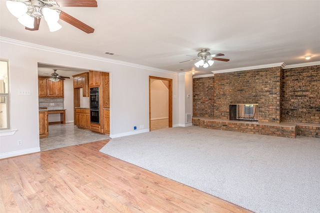 unfurnished living room with brick wall, ornamental molding, light wood-type flooring, and a fireplace