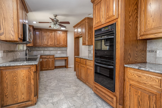 kitchen featuring sink, light stone countertops, black appliances, and decorative backsplash