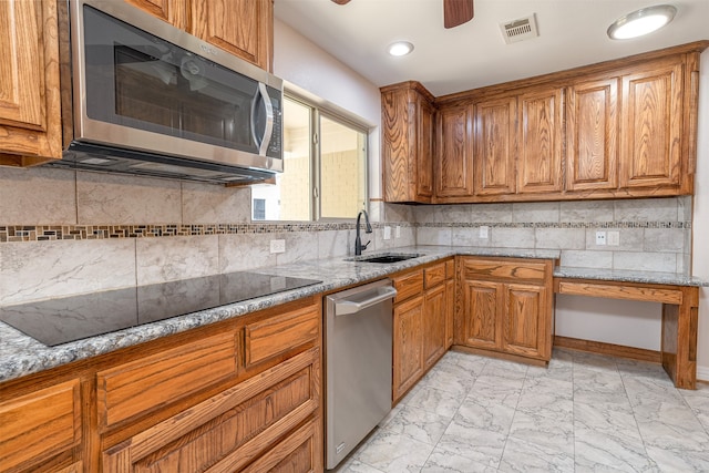 kitchen featuring sink, appliances with stainless steel finishes, light stone counters, and tasteful backsplash