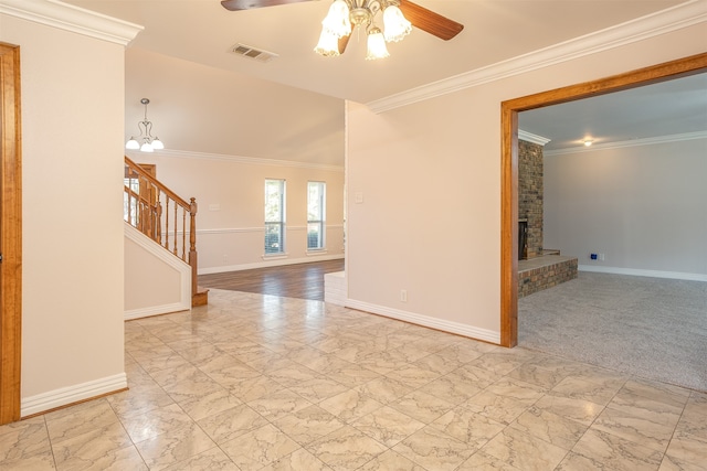 spare room featuring light colored carpet, crown molding, a fireplace, and ceiling fan with notable chandelier