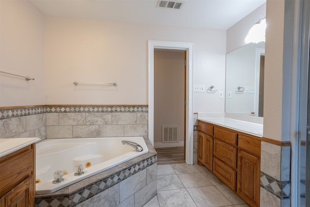 bathroom with vanity, tiled tub, and tile patterned flooring