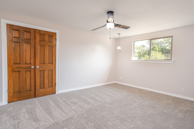 carpeted spare room featuring ceiling fan