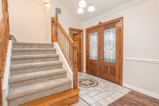 foyer featuring light hardwood / wood-style flooring, french doors, a chandelier, and vaulted ceiling