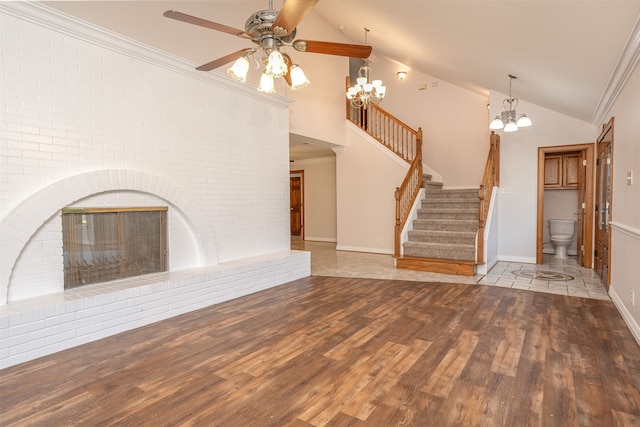 unfurnished living room featuring hardwood / wood-style floors, crown molding, a notable chandelier, a brick fireplace, and high vaulted ceiling