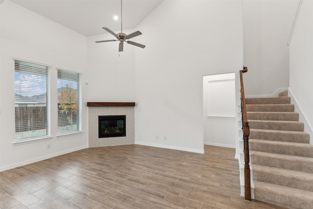 unfurnished living room with ceiling fan, light hardwood / wood-style floors, a fireplace, and high vaulted ceiling