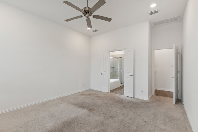 unfurnished bedroom featuring light colored carpet, ensuite bath, and ceiling fan