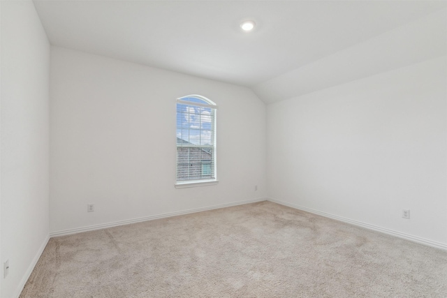 empty room with vaulted ceiling and light colored carpet