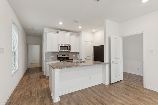 kitchen featuring white cabinets, sink, light wood-type flooring, light stone counters, and stainless steel appliances