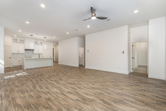 unfurnished living room featuring baseboards, visible vents, a ceiling fan, light wood-style flooring, and recessed lighting