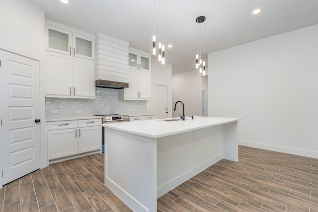 kitchen with white cabinets, a kitchen island with sink, glass insert cabinets, and light countertops