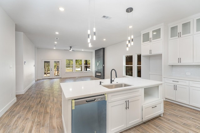 kitchen featuring a sink, open floor plan, hanging light fixtures, stainless steel dishwasher, and light countertops