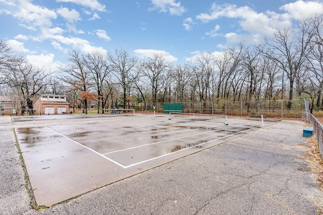 exterior space with a tennis court and fence