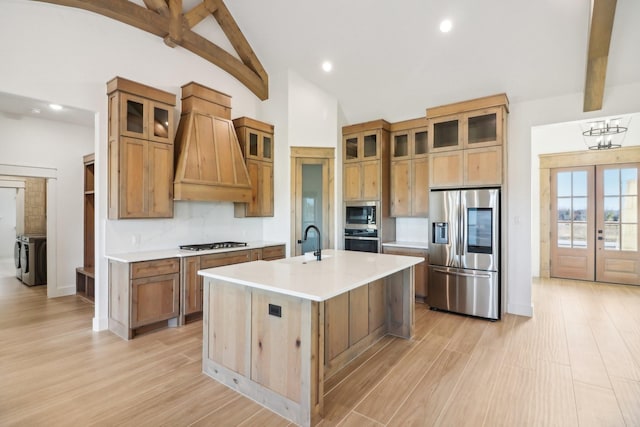 kitchen with premium range hood, french doors, an island with sink, stainless steel appliances, and beam ceiling