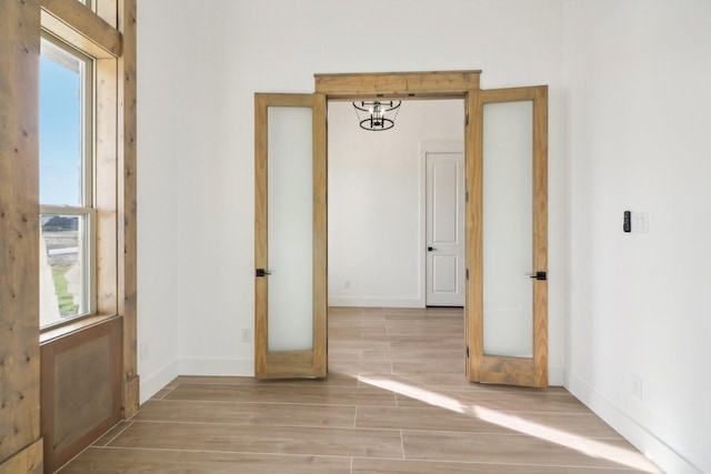 empty room with plenty of natural light, french doors, and light wood-type flooring