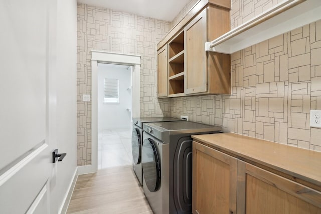 laundry area featuring washer and dryer, light hardwood / wood-style floors, and cabinets