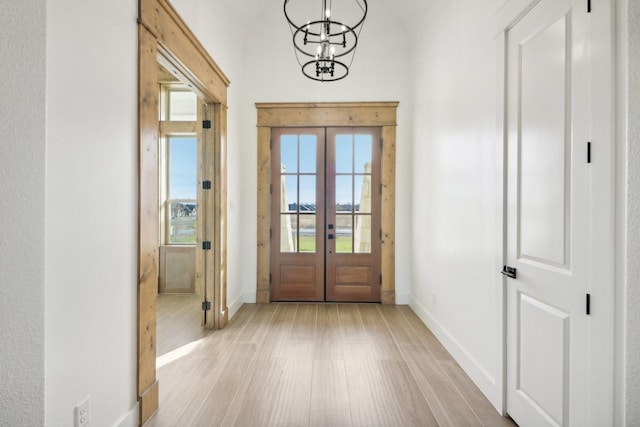 doorway featuring french doors, an inviting chandelier, and light hardwood / wood-style flooring