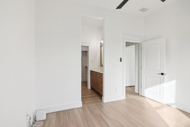 unfurnished bedroom featuring ensuite bathroom, light hardwood / wood-style floors, and ceiling fan