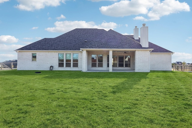 rear view of house featuring ceiling fan and a yard