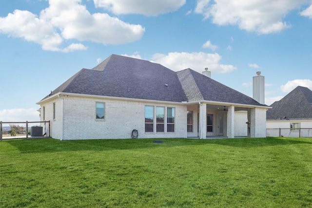 back of property featuring central air condition unit and a yard