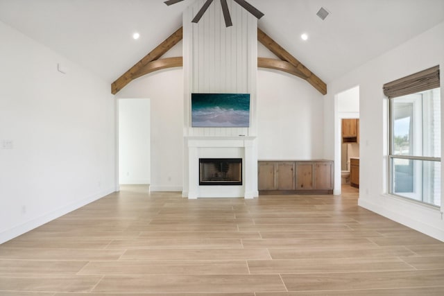 unfurnished living room featuring light wood-type flooring, vaulted ceiling with beams, and a large fireplace