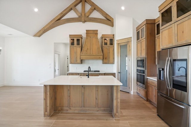 kitchen featuring premium range hood, appliances with stainless steel finishes, lofted ceiling with beams, a center island with sink, and light wood-type flooring