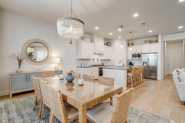 dining area featuring light hardwood / wood-style floors, a notable chandelier, and sink