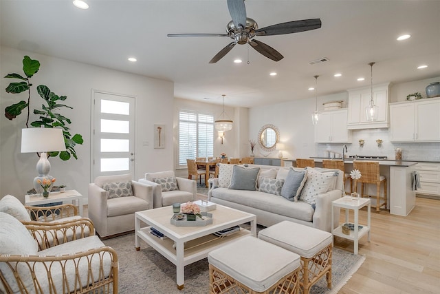 living room with light hardwood / wood-style flooring, sink, and ceiling fan