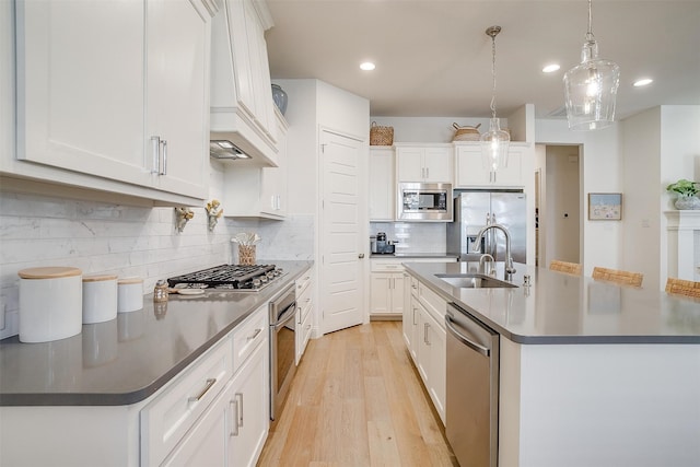 kitchen with a center island with sink, white cabinetry, decorative light fixtures, and stainless steel appliances