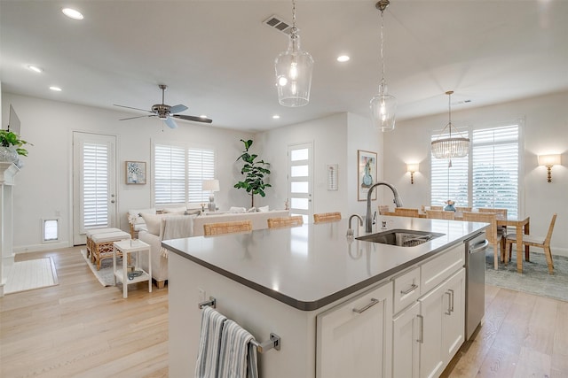 kitchen featuring white cabinets, a kitchen island with sink, sink, and plenty of natural light