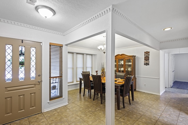 tiled entryway with ornamental molding and a chandelier