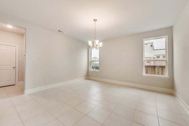 tiled spare room featuring a notable chandelier