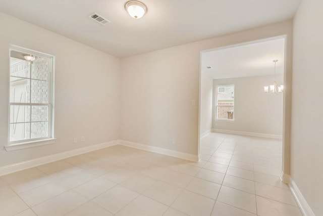 tiled spare room featuring a chandelier