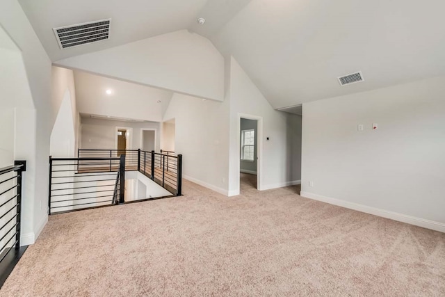 unfurnished room with light carpet and high vaulted ceiling