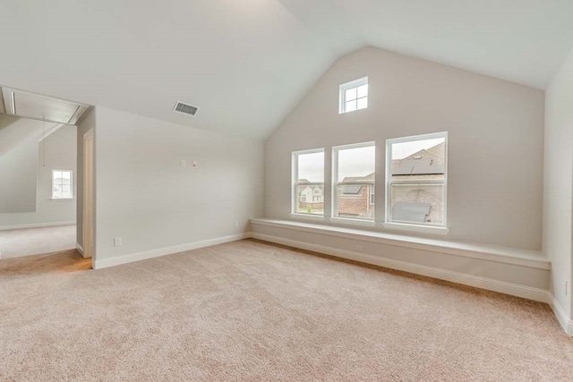 bonus room with high vaulted ceiling and light carpet