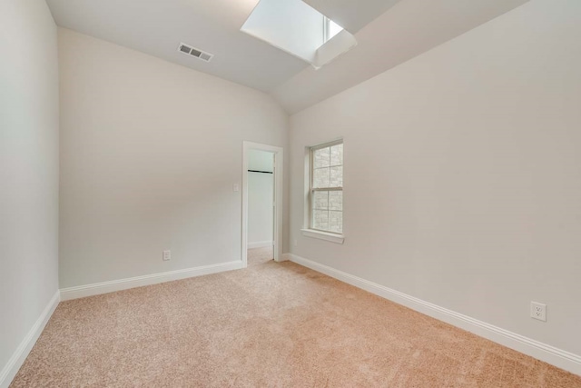 carpeted spare room with vaulted ceiling with skylight