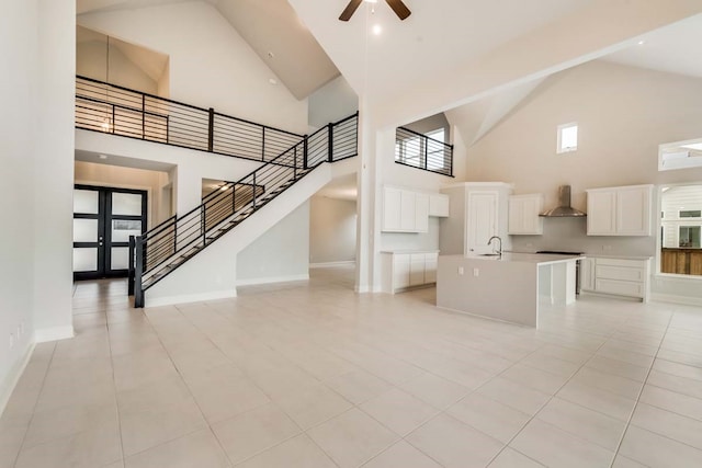 unfurnished living room with ceiling fan, sink, high vaulted ceiling, and light tile patterned floors