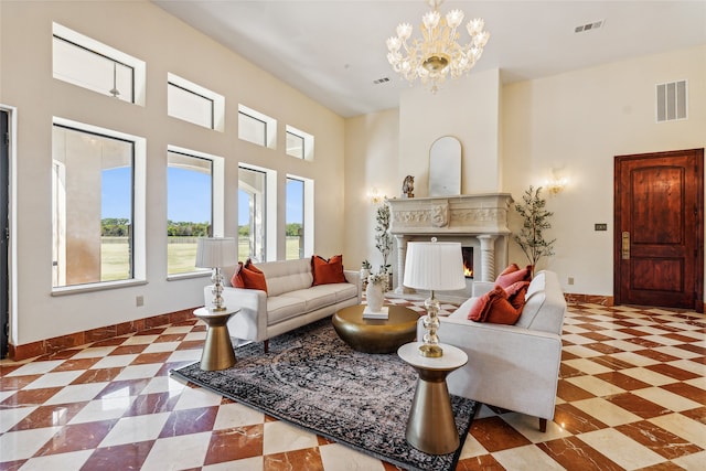 living room featuring a premium fireplace, an inviting chandelier, and a towering ceiling