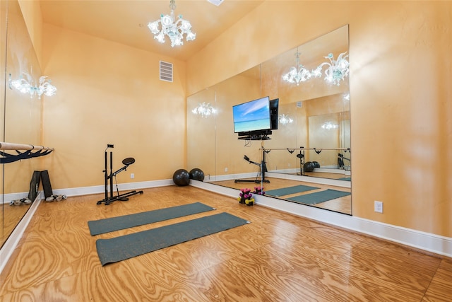 exercise room featuring an inviting chandelier and high vaulted ceiling