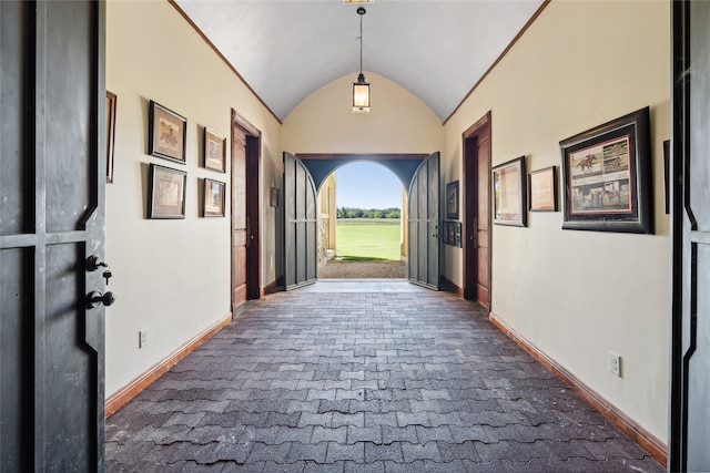 hall with lofted ceiling and dark carpet